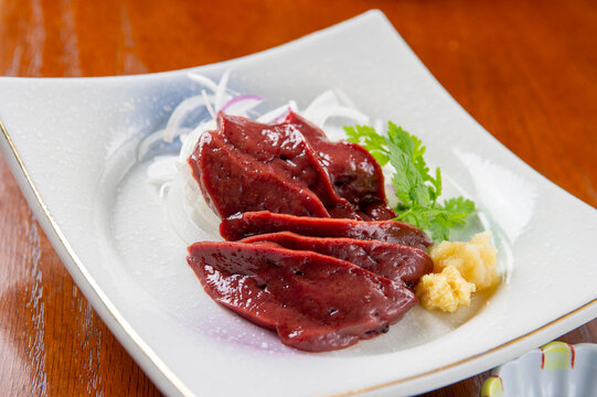 Fresh sliced beef liver sashimi elegantly plated with wasabi and grated daikon