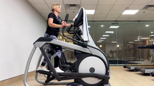 A person is exercising on a fitness machine at a gym. The workout focuses on strength and endurance. The gym is well-lit and spacious.