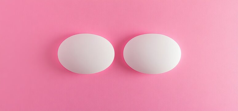 Two white pills on solid pink background
