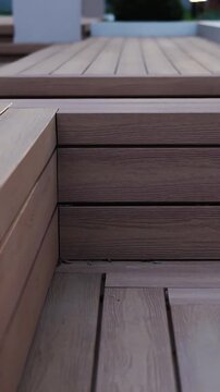 Vertical video. Close-up of a modern wooden terrace with clean lines near a contemporary outdoor patio.