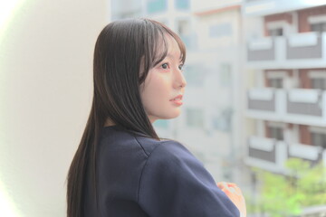 Fototapeta premium ベランダから見える景色を眺めて休憩する女性