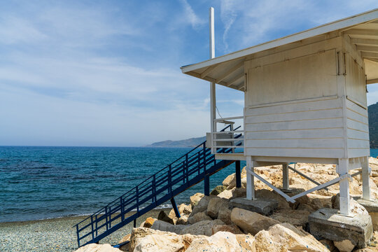 White wooden lifeguard tower on beach in Pomos, Cyprus. Peaceful Mediterranean coastline, beach safety, summer travel, seaside relaxation and coastal tourism concept.