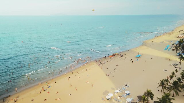 Danang city aerial view showing vibrant my khe beach activity, people swimming, relaxing on sand, parasailing, enjoying summer holiday vacation, tropical coastline travel destination