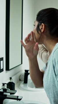 Woman, mirror and inspection in bathroom for skincare, acne breakout and skin irritation. Female person, reflection and check in home for facial blemish, clogged pores and dermatology issues with zit