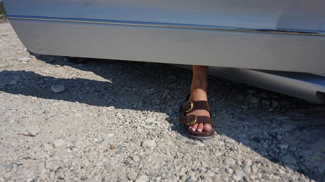 Woman's feet stepping out of a car onto a gravel road