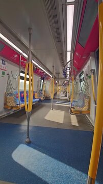 Passenger point of view vertical shot inside a moving MRT Putrajaya Line train carriage, showcasing the contemporary transit interior design and urban public transportation in Malaysia.