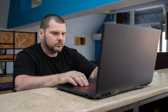 focused man works on a laptop at a kitchen counter, illustrating remote employment, online business and flexible home office productivity in a contemporary apartment