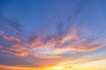 Fototapeta premium Golden Sunset Clouds against Deep Blue Sky,A breathtaking view of wispy, golden-lit clouds scattered across a deep blue evening sky at sunset, creating a peaceful and serene atmosphere.