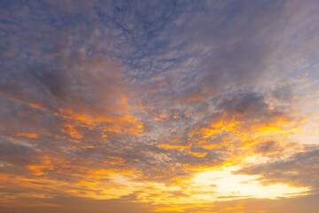 Obraz premium Golden Sunset Sky with Dramatic Clouds,A breathtaking view of a vibrant golden sunset sky filled with textured clouds, creating a peaceful and inspiring atmosphere.