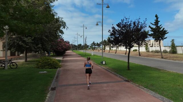 Female runner in activewear burning calories with a cardio workout. Sporty woman jogging running on city park bridge outdoors. Woman exercising with earphones on in the morning. Copy space Stock Photo