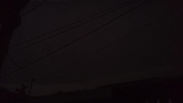 Dramatic Night Sky Featuring A Sudden Flash Of Bright Lightning Illuminating Clouds Above Residential Power Lines And Silhouetted Rooftops