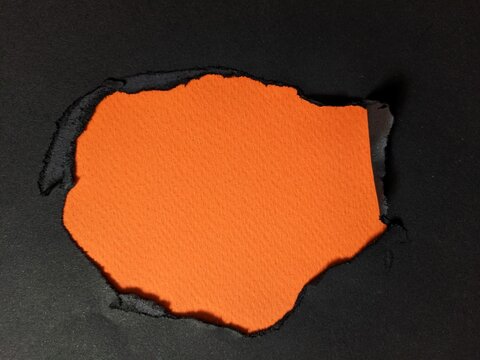 Torn orange paper with rough edges on dark background, highlighting texture and design concept for creative projects.