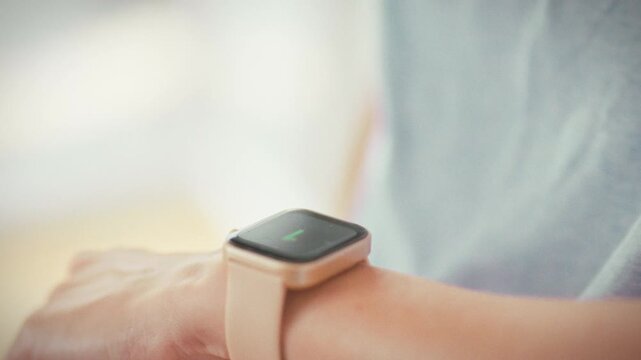 Focusing on her smartwatch screen, a girl watches the countdown begin, marking the start of her workout. The glowing display highlights the timer, building anticipation as she prepares to train