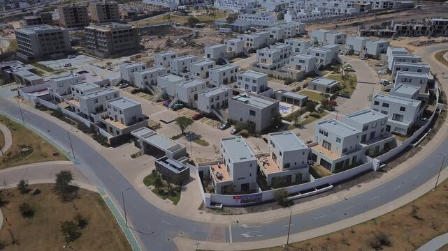 Drone orbital view of Queretaro residential neighborhood development featuring three story duplex units apartment buildings and community park space