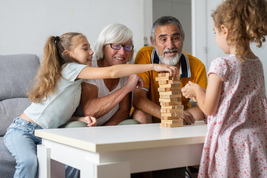 Happy Grandparents Playing Wooden Block Tower Game with Their Granddaughters