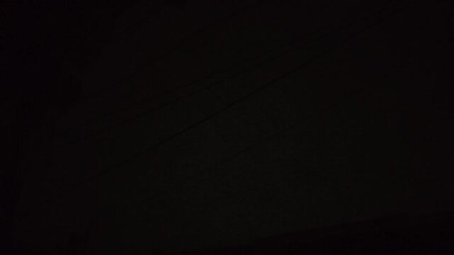 Bright bolt of lightning strikes through the dark night sky creating a dramatic electrical atmospheric storm display