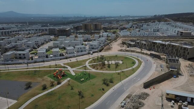 Drone orbital view of Queretaro residential neighborhood development featuring three story duplex units apartment buildings and community park space