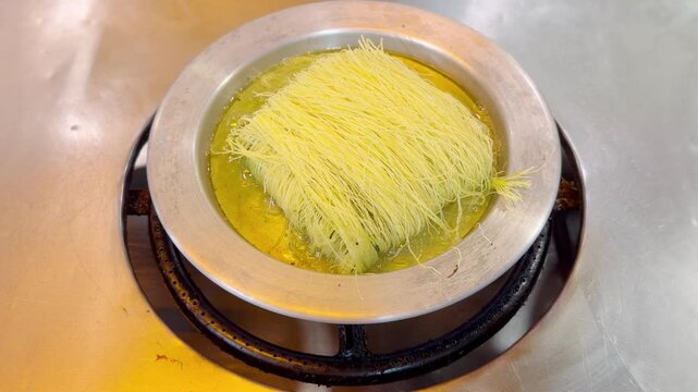 Cooking Process &ndash; Frying Traditional Turkish Kadayıf Pastry in a Large Skillet on a Stove Top.Frying Kadayıf on the Stove &ndash; Turkish Dessert Preparation