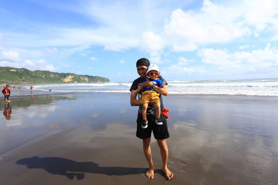 June 15 2019 Yogyakarta Indonesia Man Holding Young Child Standing on Wet Sand Mirror Reflection at Parangtritis Beach