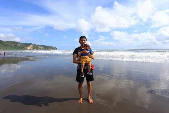 June 15 2019 Yogyakarta Indonesia Man Holding Young Child Standing on Wet Sand Mirror Reflection at Parangtritis Beach