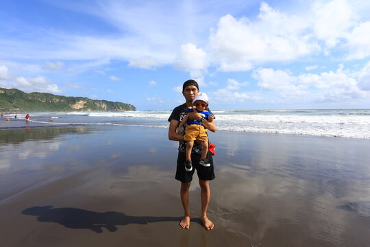 June 15 2019 Yogyakarta Indonesia Man Holding Young Child Standing on Wet Sand Mirror Reflection at Parangtritis Beach