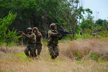 Fototapeta premium group of soldiers in military uniforms carrying BB guns were randomly attacked and taken down during a military exercise while playing a game.