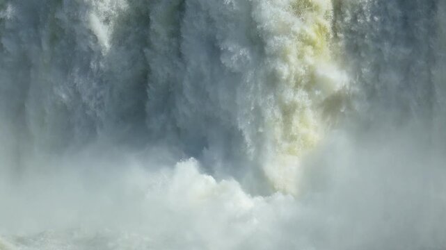 Immense volumes of water plunging down the magnificent iguazu falls on the border of argentina and brazil, creating mist and foam
