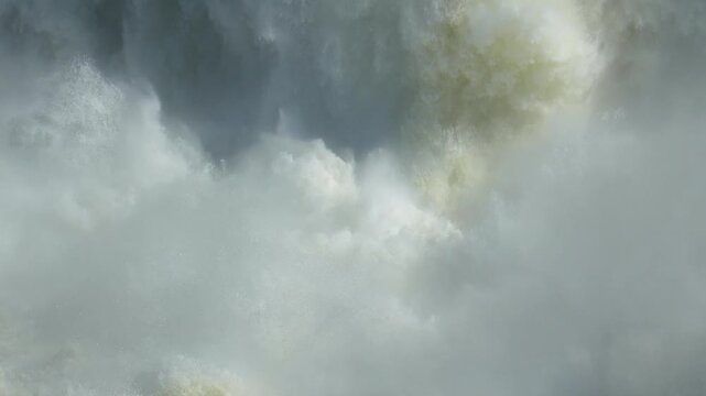 Tremendous volume of water cascading over the falls, creating a powerful and misty spectacle. A close up view of the raw force of nature