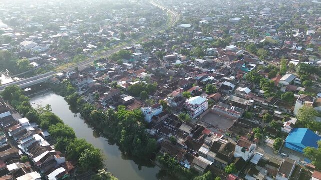 Aerial view of railway tracks cutting through Surakarta city center at sunset, Solo, Central Java, Indonesia. Drone shot of urban railroad infrastructure during warm afternoon light.