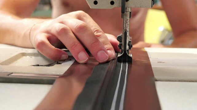 Person sewing zipper on fabric with industrial sewing machine