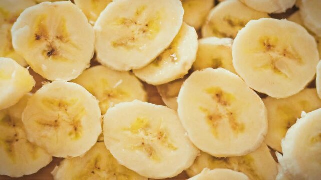 Thinly sliced yellow banana pieces are randomly piled in layers on plate, forming three-dimensional texture. This fruit arrangement highlights nutrition, healthy-eating concepts benefits of bananas