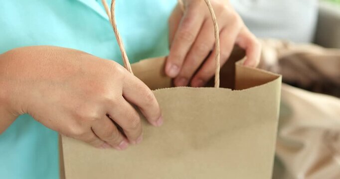 Woman hands opening and checking inside a paper shopping bag, shopping, retail, delivery, unboxing, packaging, eco-friendly products, and consumer lifestyle, close-up