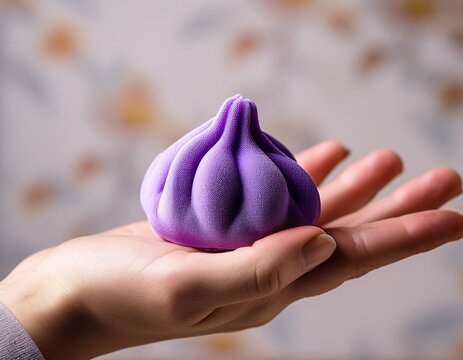 hand holding purple dumpling stress squishy toy