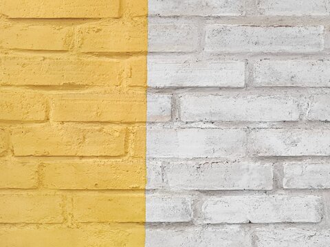 Background of rough-textured wall with a minimalist two-tone concept vertically, vibrant yellow and white, up close. Surface of handmade aesthetic modern brick wall rough with uneven dual-tone paint.