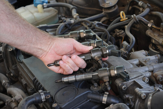 Detail of modern diesel engine repair, closeup of injector in mechanic hand, common rail system