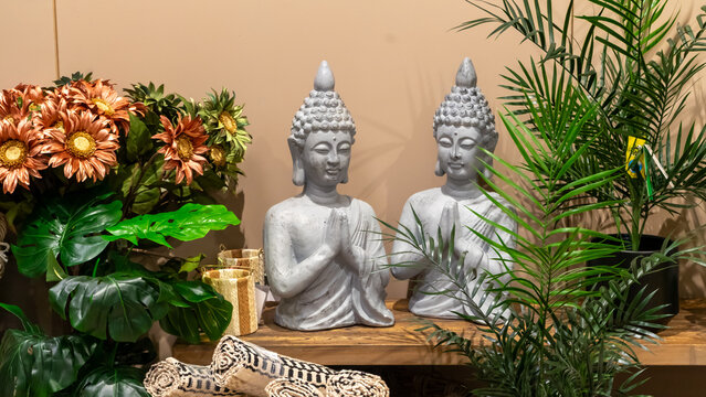Grey decorative Buddha figurines in a semi-seated position, with arms spread and hands in a gesture of prayerful greeting