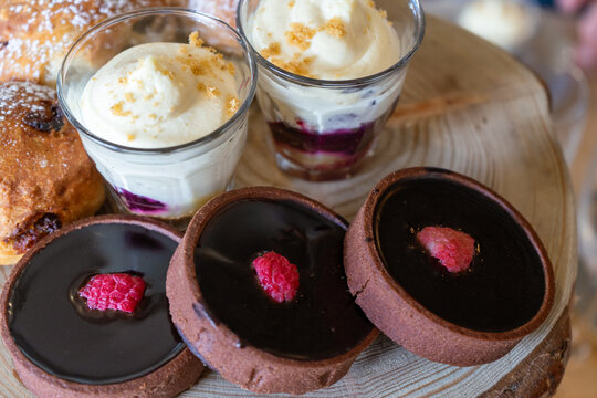 Individual-portion desserts, including chocolate tartlets with raspberries and creamy desserts in glasses closeup