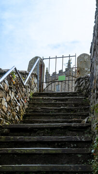 Stone steps leading to a metal gate against the backdrop of an old stone building resembling a church, castle, or fortress