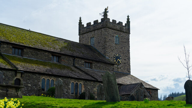 St Michael & All Angels Church, Hawkshead, Lake District, England. A stone church with a distinctive crenellated tower and a clock on it