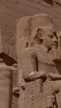 Close-up of giant Ramesses II colossi carved into rock facade at Abu Simbel temple, Egypt. Dramatic upward view of ancient sandstone pharaoh statues. Travel and history.