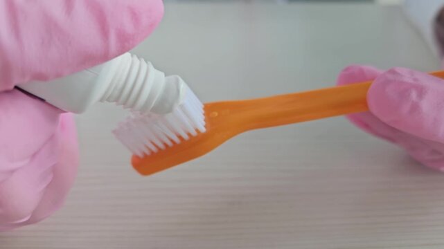 Brushing teeth with orange toothbrush and white toothpaste in a bathroom setting