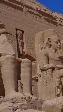 Close-up of giant Ramesses II colossi carved into rock facade at Abu Simbel temple, Egypt. Dramatic upward view of ancient sandstone pharaoh statues. Travel and history.