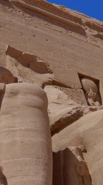 Close-up of giant Ramesses II colossi carved into rock facade at Abu Simbel temple, Egypt. Dramatic upward view of ancient sandstone pharaoh statues. Travel and history.