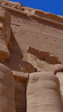 Close-up of giant Ramesses II colossi carved into rock facade at Abu Simbel temple, Egypt. Dramatic upward view of ancient sandstone pharaoh statues. Travel and history.