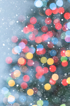 Colorful Christmas Tree Bokeh on Light Blue Background with Snow