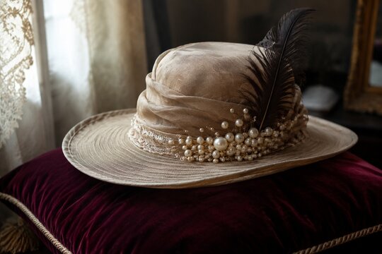 A vintage wide-brimmed hat with pearls and a feather on a velvet cushion.
