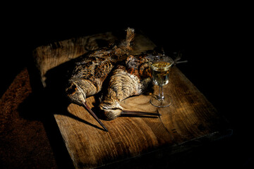 Fototapeta premium Woodcock game birds on rustic wooden table with glass of white wine