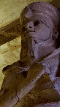Symmetrical row of colossal Ramesses II osiride pillars lining both sides of main hall at Abu Simbel temple, Egypt, faded painted ceiling with vultures above.