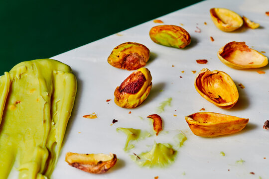 a thick pistachio spread lies beside cracked shells on a table