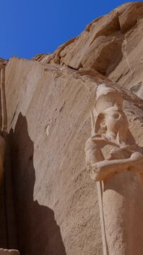 Close-up of giant Ramesses II colossi carved into rock facade at Abu Simbel temple, Egypt. Dramatic upward view of ancient sandstone pharaoh statues. Travel and history.